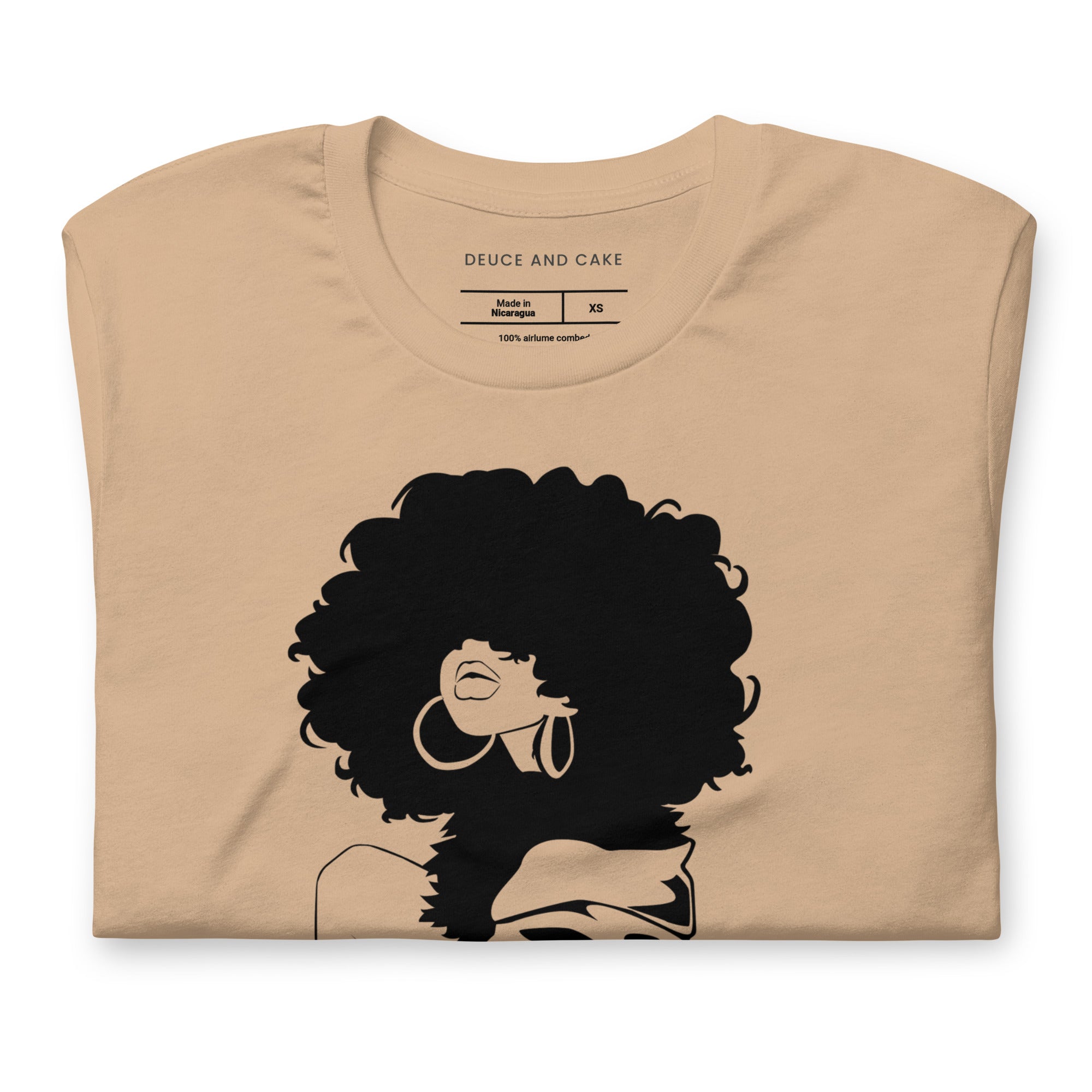 Tan t-shirt with a graphic of woman with afro and wearing a sweater.